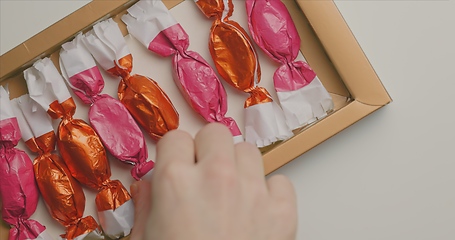 Image showing Man and woman picking out christmas chocolate from box