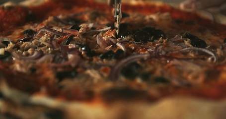 Image showing Delicious pizza being sliced up on the table