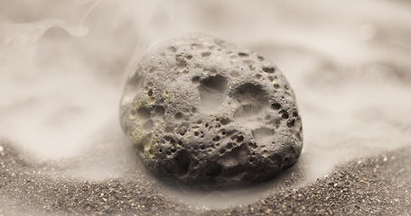 Image showing Smoke whirling around small meteorite stone