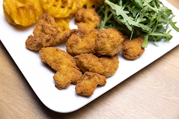 Image showing Chicken nuggets with salad on table closeup