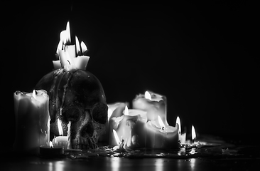 Image showing Candles and human skull in darkness closeup in black and whiter