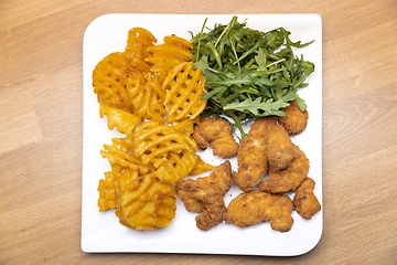 Image showing Chicken nuggets with salad on table closeup