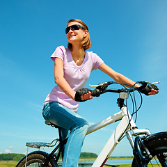 Image showing Young woman is sitting on her bicycle