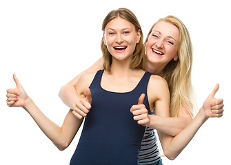 Image showing Two young happy women showing thumb up sign