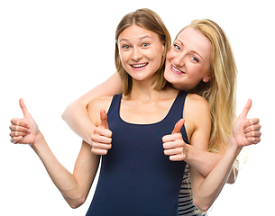 Image showing Two young happy women showing thumb up sign