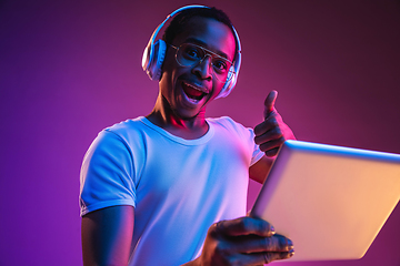 Image showing Young african-american man\'s listening to music in neon light