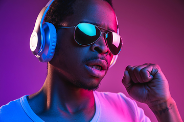 Image showing Young african-american man\'s listening to music in neon light