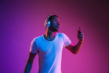 Image showing Young african-american man\'s listening to music in neon light