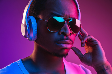 Image showing Young african-american man\'s listening to music in neon light