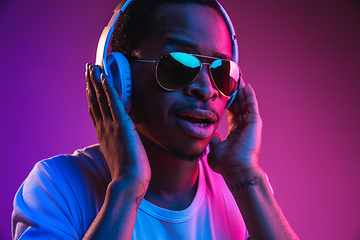 Image showing Young african-american man\'s listening to music in neon light