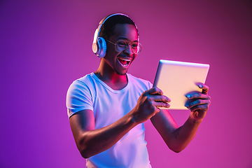 Image showing Young african-american man\'s listening to music in neon light