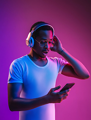 Image showing Young african-american man\'s listening to music in neon light