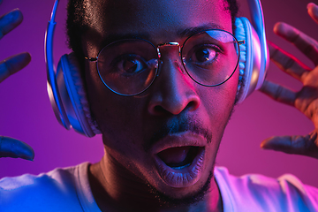 Image showing Young african-american man\'s listening to music in neon light