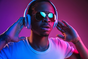 Image showing Young african-american man\'s listening to music in neon light