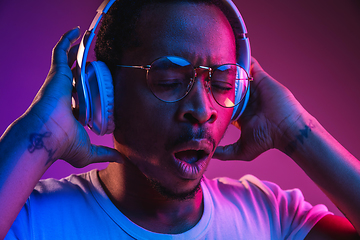 Image showing Young african-american man\'s listening to music in neon light