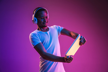 Image showing Young african-american man\'s listening to music in neon light