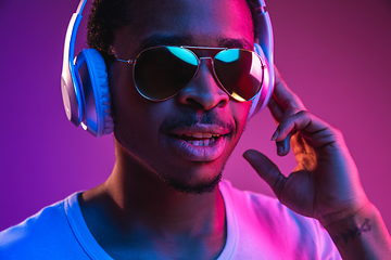 Image showing Young african-american man\'s listening to music in neon light