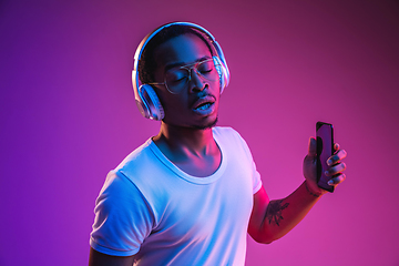 Image showing Young african-american man\'s listening to music in neon light