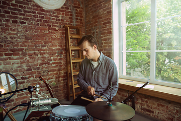 Image showing Young man recording music, playing drums and singing at home