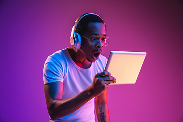 Image showing Young african-american man\'s listening to music in neon light