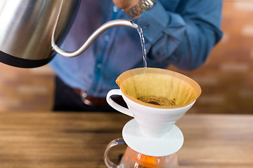 Image showing Barista pouring water on coffee filter