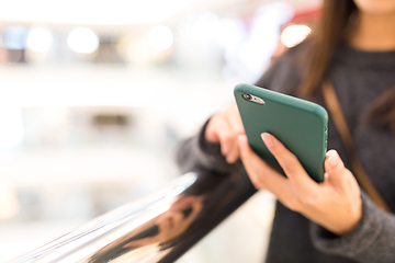 Image showing Woman sending sms on mobile phone in shopping mall