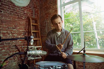 Image showing Young man recording music, playing drums and singing at home