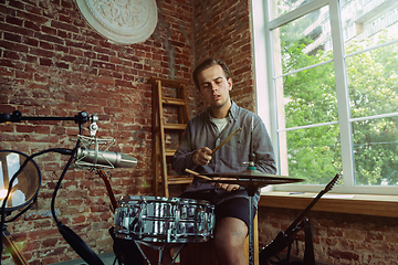 Image showing Young man recording music, playing drums and singing at home