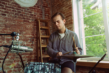 Image showing Young man recording music, playing drums and singing at home