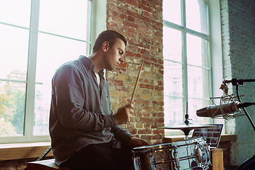 Image showing Young man recording music, playing drums and singing at home