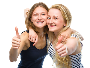 Image showing Two young happy women showing thumb up sign