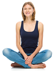 Image showing Young happy woman is sitting on the floor