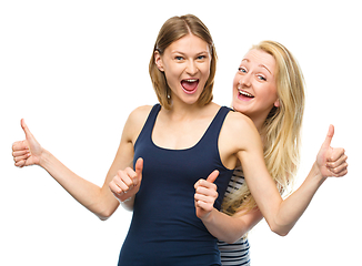 Image showing Two young happy women showing thumb up sign