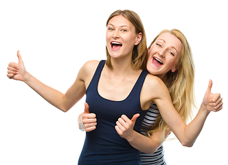 Image showing Two young happy women showing thumb up sign