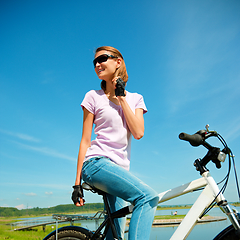 Image showing Young woman is sitting on her bicycle