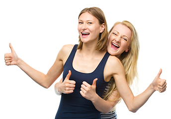 Image showing Two young happy women showing thumb up sign