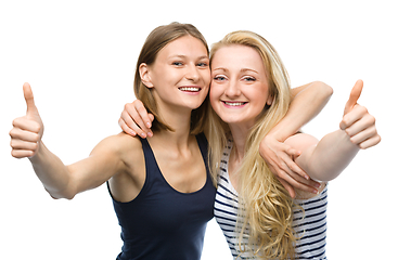 Image showing Two young happy women showing thumb up sign