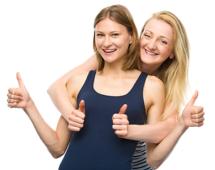 Image showing Two young happy women showing thumb up sign