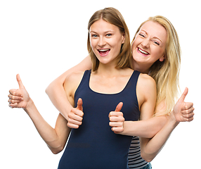 Image showing Two young happy women showing thumb up sign