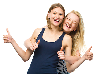 Image showing Two young happy women showing thumb up sign