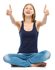 Image showing Young happy woman is showing thumb up sign