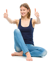 Image showing Young happy woman is showing thumb up sign