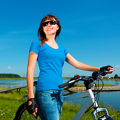 Image showing Young woman is standing in front of her bicycle