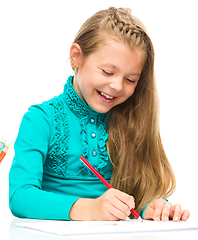 Image showing Little girl is drawing using pencils
