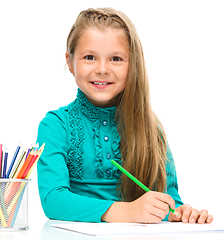 Image showing Little girl is drawing using pencils