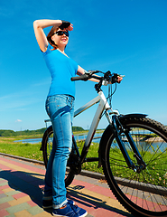 Image showing Young woman is standing in front of her bicycle