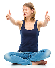 Image showing Young happy woman is showing thumb up sign