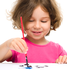 Image showing Little girl is painting with gouache