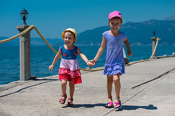 Image showing little sisters running on the beach coast