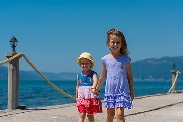 Image showing little sisters walking on the beach coast